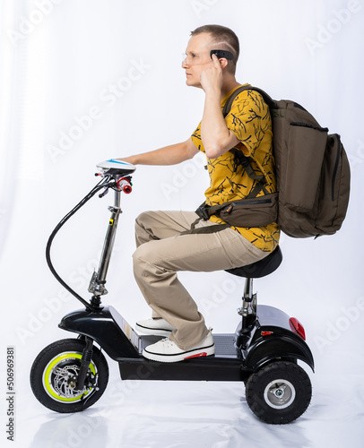 guy in an electric car. a man in the studio on a tricycle with a backpack and interactive glasses. travel white background. electric scooter. ecological transport