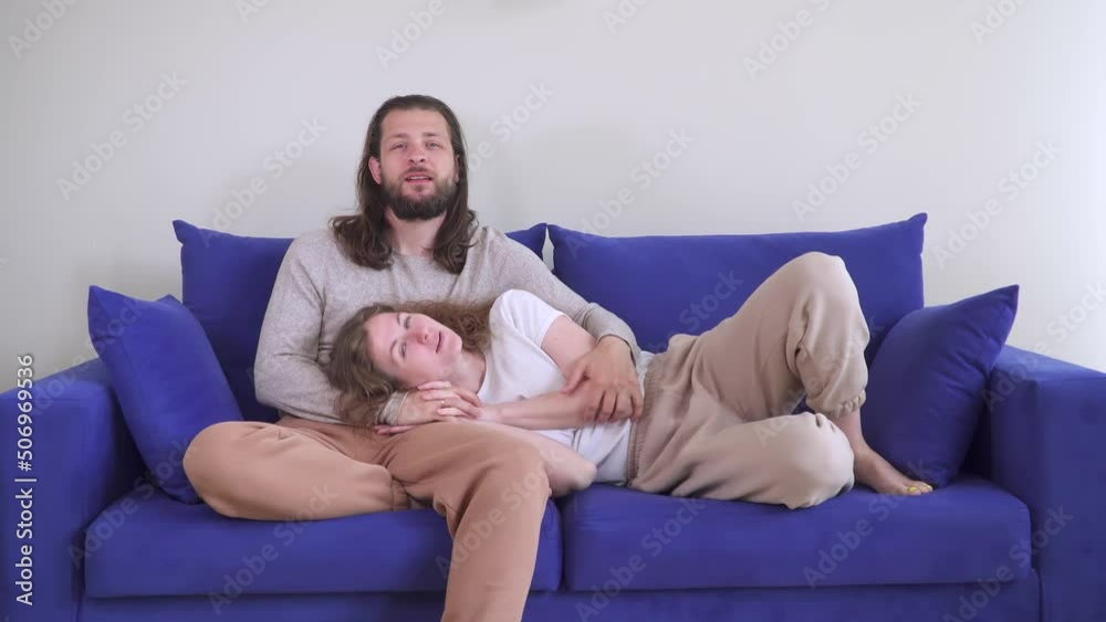 lay woman head on man knees. couple is sitting on couch hugging. Kiss of two lovers on blue sofa. Caucasian man and woman in cozy house spend time and weekends together. Be happy with each other. lay woman head on man knees. couple is sitting on couch hugging. Kiss of two lovers on blue sofa. Caucasian man and woman in cozy house spend time and weekends together. Be happy with each other.