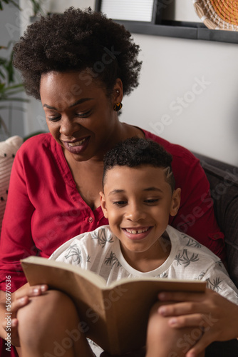 Mãe e filho jovem lê livro juntos na sala de casa