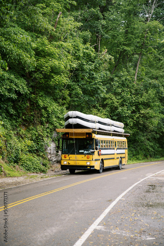 A bus transports a load of white water rafts strapped to the roof through the Smoky Mountains.