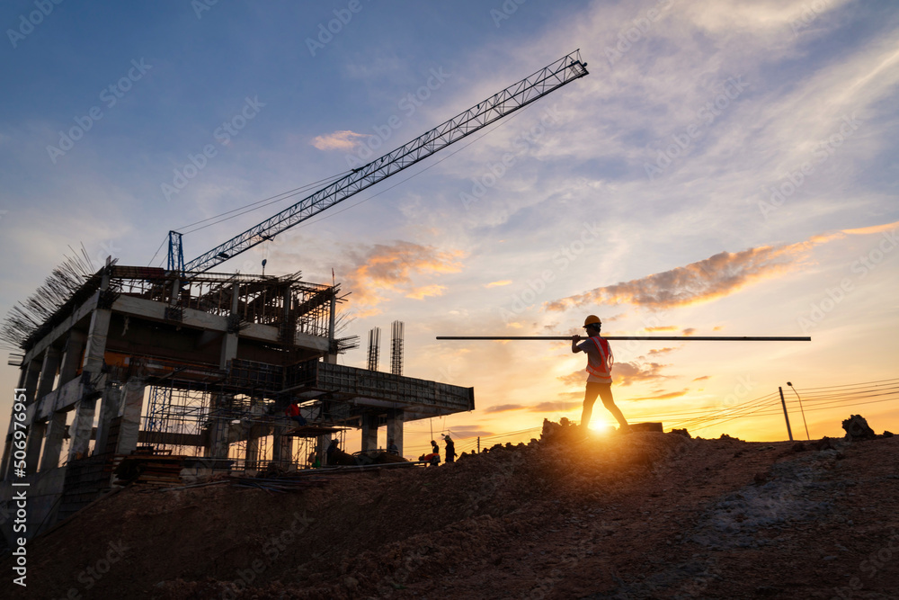 A construction worker in construction site at sunset in evening time. Silhouette of construction.