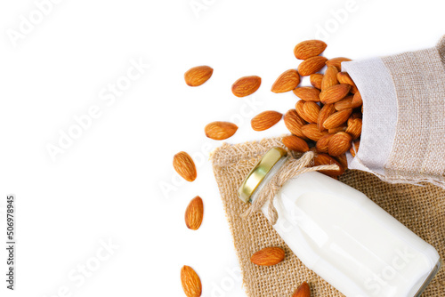 glass bottle of milk with almond in hemp fabric bag on white background.