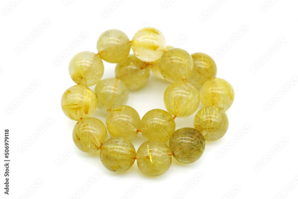 Fototapeta premium Rutile in quartz gemstone on rock background. Rutile quartz stone beads.