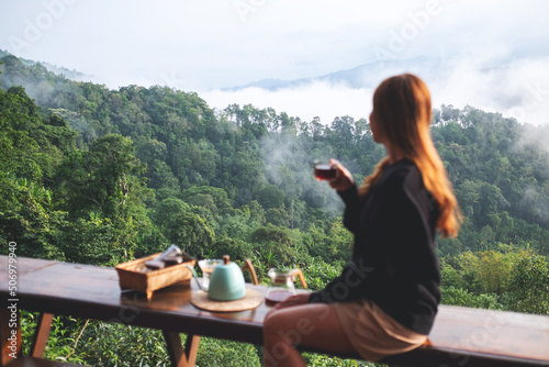 Blurred of a young woman making and drinking drip coffee while looking at a beautiful mountain and nature view