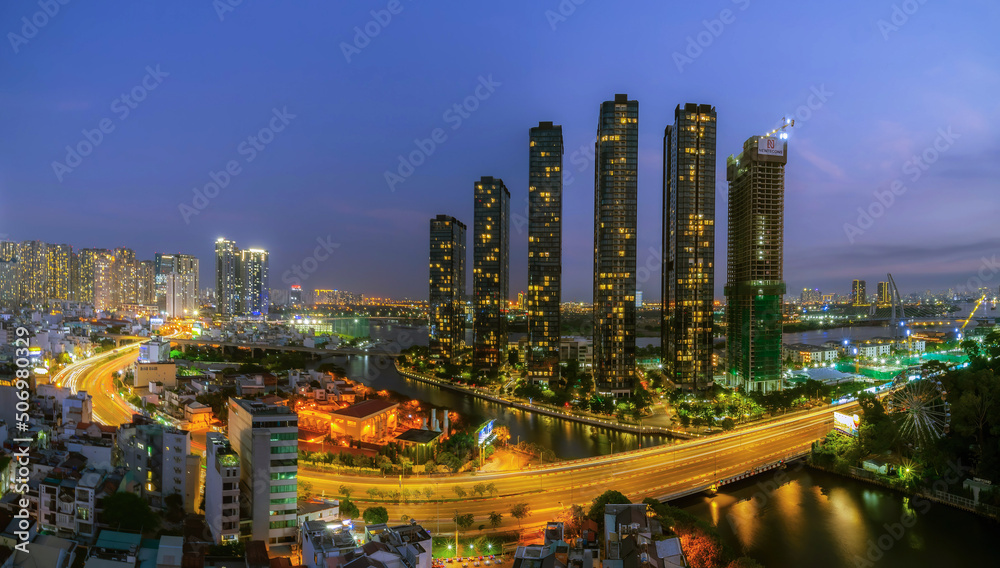 Naklejka premium Aerial view of Bitexco Tower, buildings, roads, Thu Thiem 2 bridge and Saigon river in Ho Chi Minh city - Far away is Landmark 81 skyscraper. Travel concept.
