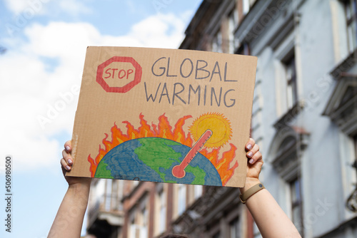 Protester holding sign with slogan Stop Global Warming. Woman with placard at protest rally demonstration, strike against climate change. © Longfin Media