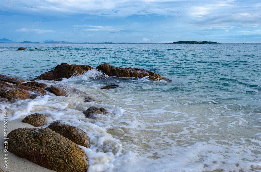 White waves impact rocks on the beach in beautiful blue sea White waves impact rocks on the beach in beautiful blue sea