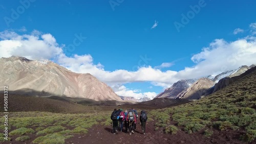 Group of young people walking on the mountain and talking on a sunny day