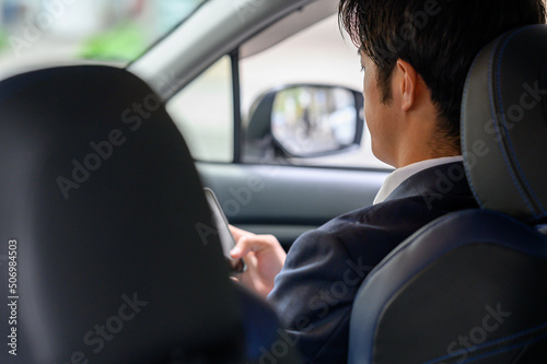 運転席でスマートフォンを操作する男性　 © Peak River