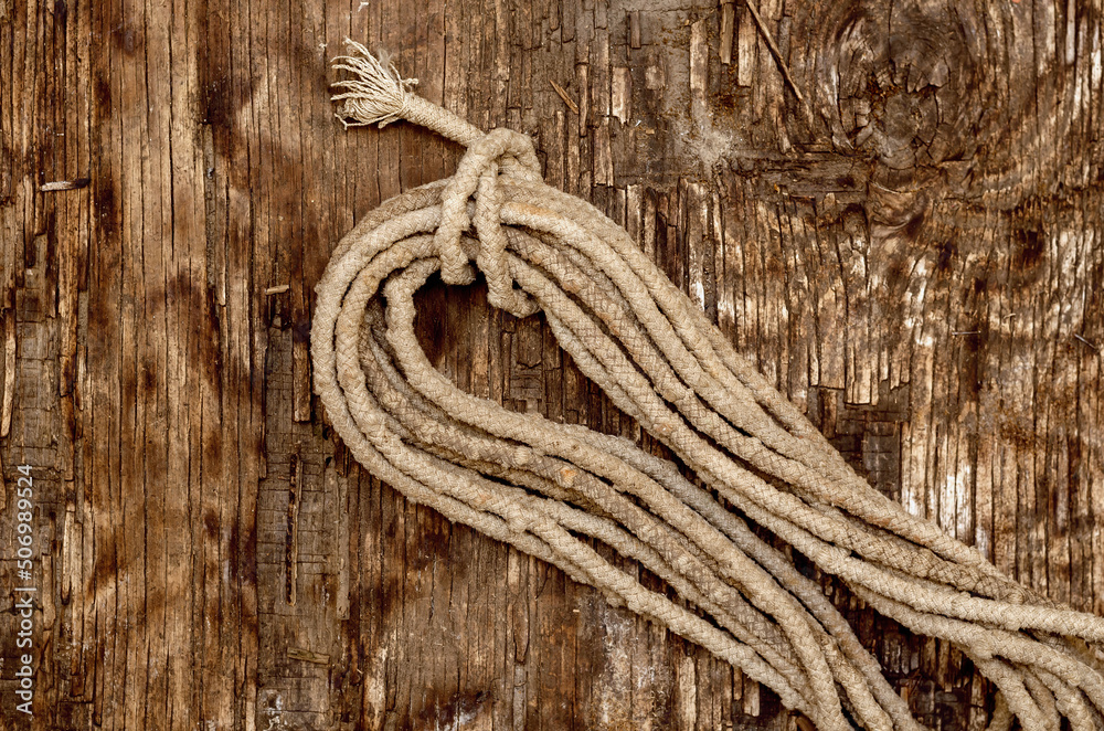 Coil of old rope on a dark wooden background. Worn, dirty rope.