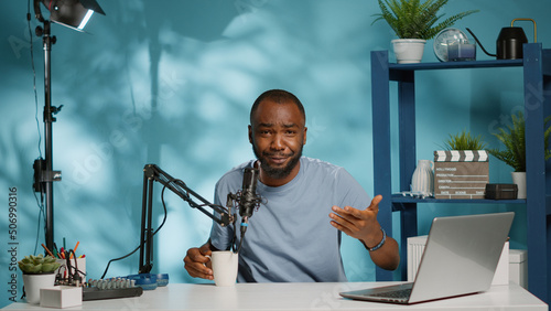 POV of influencer recording vlog and talking to subscribers on camera. Vlogger using microphone and laptop to film video for podcast channel on social media. Man creating content