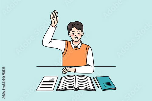 Active schoolboy sitting at desk in class raise hand volunteer to answer. Smart boy child participate in discussion at lesson. Clever kid at class. Education concept. Vector illustration. 