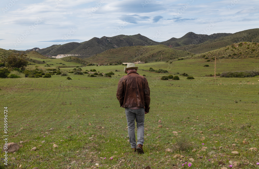 Rear view of adult man in cowboy hat on field Rear view of adult man in cowboy hat on field
