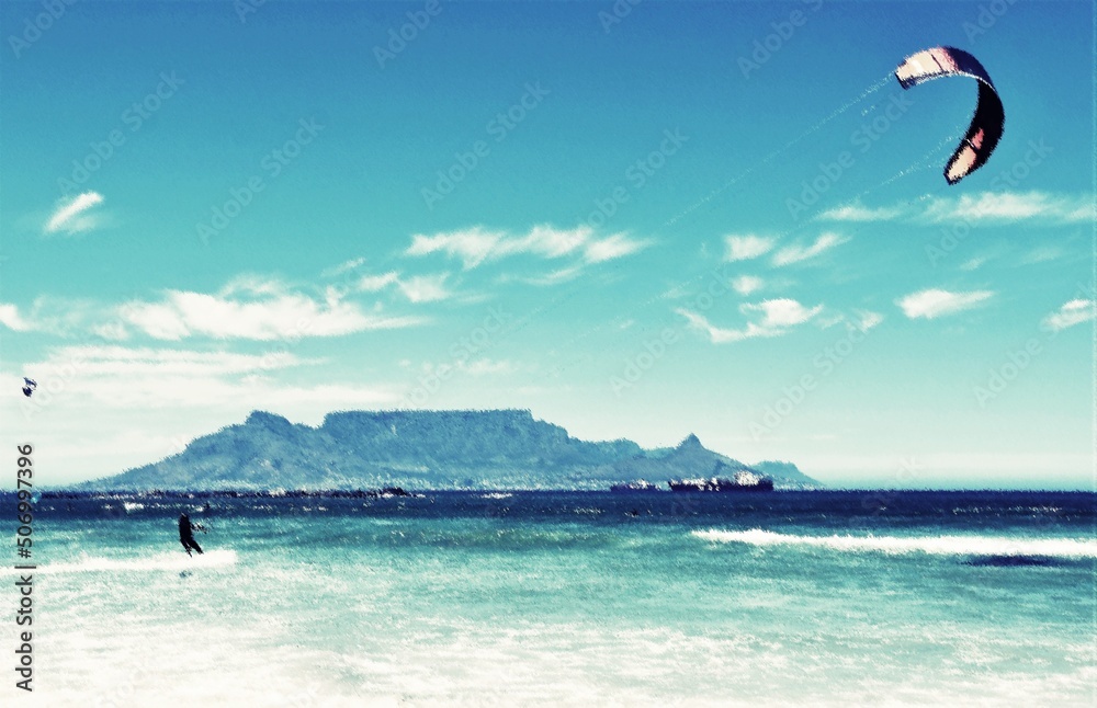 Fototapeta premium Landscape with kite surfer having fun on the Atlantic ocean and Table Mountain in the background mixed media