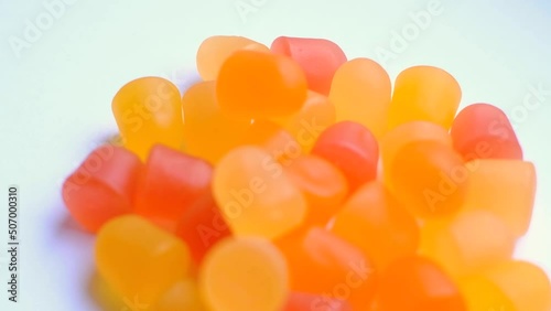 Close-up texture of orange and yellow multivitamin gummies in the form of bears on white background. 