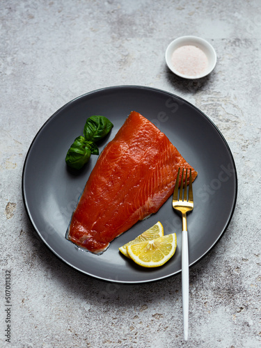 Half of salted salmon fillet on a gray plate. Healthy eating