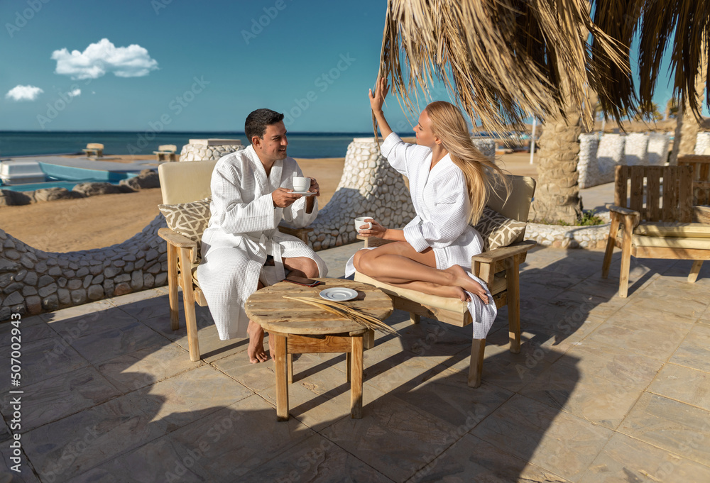 Young couple man and woman - morning coffee at the warm seashore