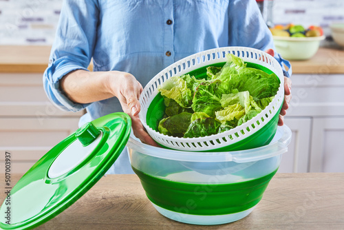 Foto Crop female taking lettuce from spinner