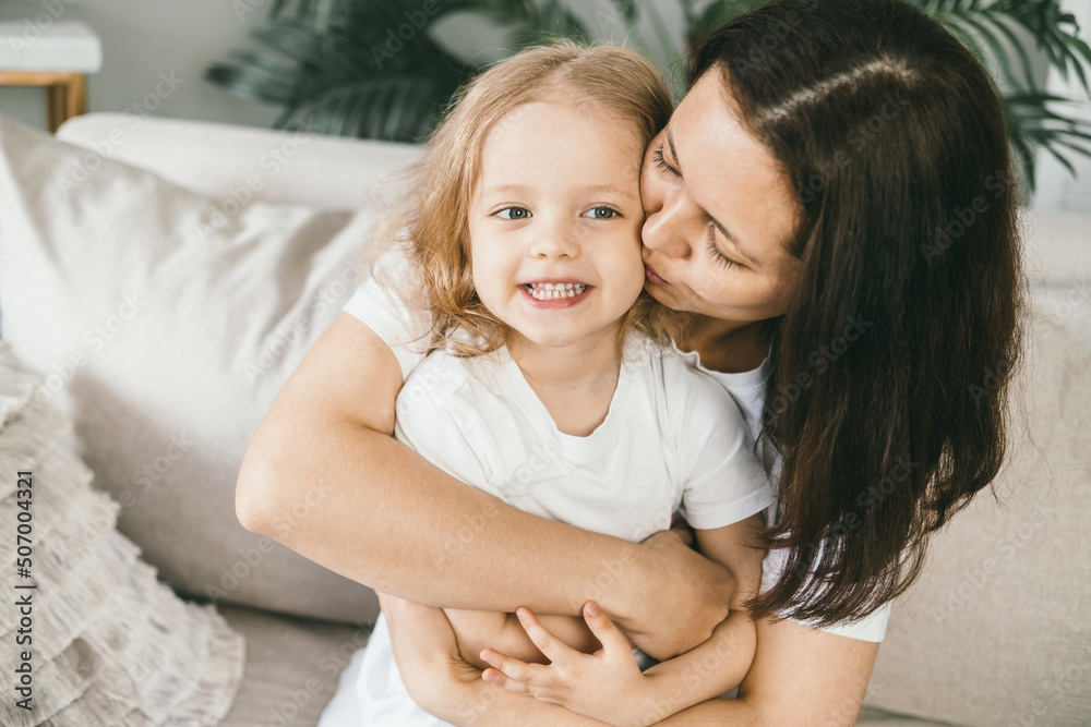 A mother tenderly kisses her four-year-old daughter. A mother tenderly kisses her four-year-old daughter.