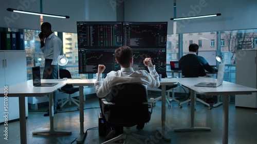 Back view of stock market investor doing winner gesture and celebrating profit