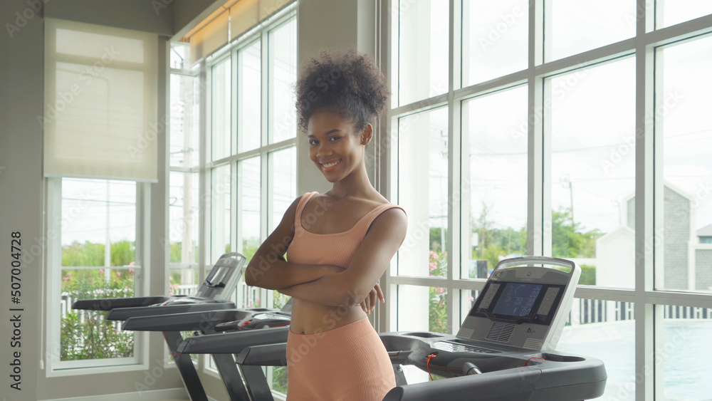 Fototapeta premium Portrait of Black African American woman at gym fitness center club. Muscle strength training workout. Exercise indoor with sport equipment. Athletic. People lifestyle. Recreation.