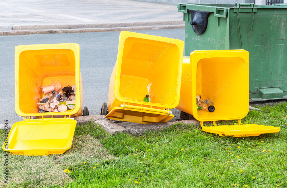 Overturned yellow plastic trash containers lie on the street