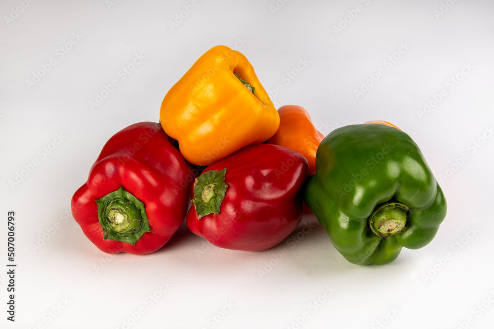 Red, green, yellow and orange bell peppers on a white background Red, green, yellow and orange bell peppers on a white background