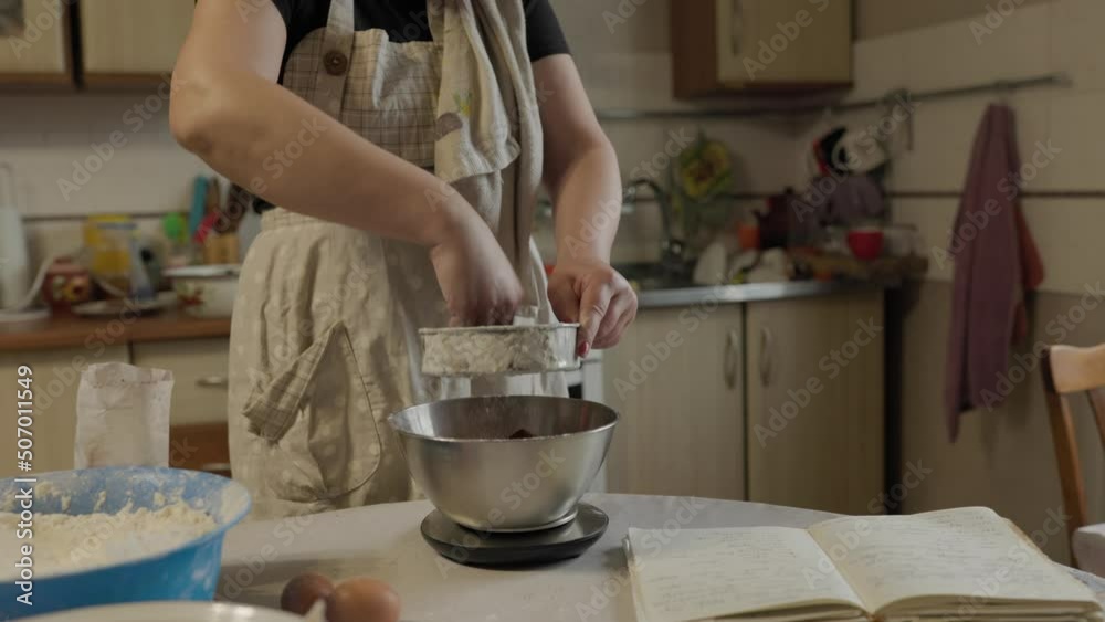 Close-up of bakery concept - Woman sift cocoa powder through metallic sieve to glass bowl for baking Close-up of bakery concept - Woman sift cocoa powder through metallic sieve to glass bowl for baking