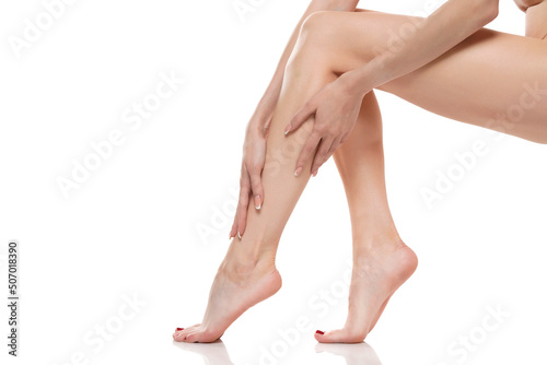 Young woman touching her smooth long legs, and putting on moisturizer after shaving her legs © vladimirfloyd