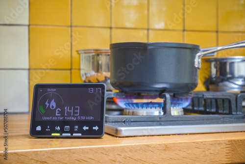 Smart meter placed next to gas stove with blue flames burning