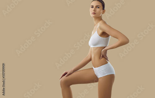 Portrait of sexy young woman in underwear posing on yellow studio background. Toned sporty female model advertise underclothing garment or clothes set for sport. Advertisement concept. Copy space. © Studio Romantic