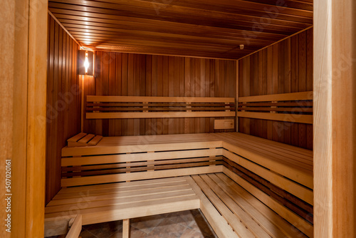 Seat in sauna room. Empty wooden steam room with stone heater.Sauna room for good health. Sauna room with traditional sauna accessories.Healthy and spa life style. 