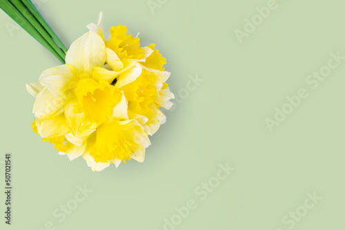 Bouquet of yellow daffodils, narcissus on green background with copy space. Mockup, template for holiday, birthday, mother's day on yellow background with copy space for text. Top view, flat lay.