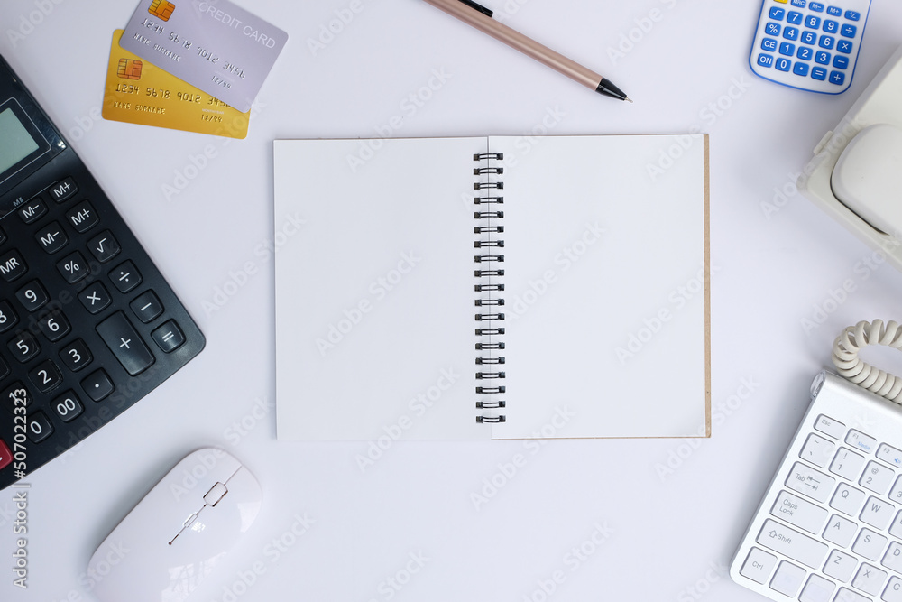 Office desk with smartphone, laptop computer, cup of coffee, and office tools. Flat lay, top view with copy space. A bank notepad and a pen are on top of an office desk table containing computer tools Office desk with smartphone, laptop computer, cup of coffee, and office tools. Flat lay, top view with copy space. A bank notepad and a pen are on top of an office desk table containing computer tools