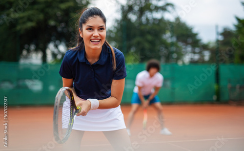 Tennis sport people concept. Mixed doubles player hitting tennis ball with partner standing near net © NDABCREATIVITY