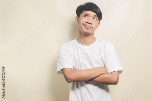 asian man wearing white t-shirt in doubt and thinking on isolated background