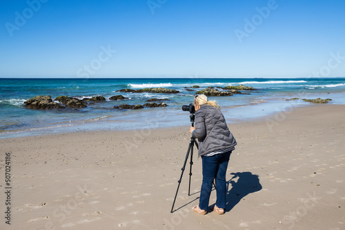 Woman Photographer with Tripod on Beach