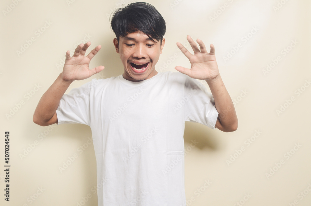 asian man wearing white t-shirt with surprised expression on isolated background asian man wearing white t-shirt with surprised expression on isolated background