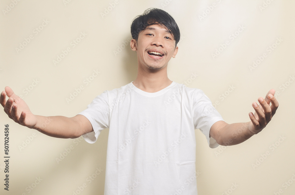 asian man wearing white t-shirt with welcome gesture isolated background asian man wearing white t-shirt with welcome gesture isolated background