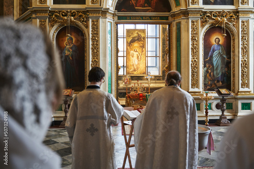 Fotografiet two Orthodox priests in cassocks, seen from the back, standing in front of an op