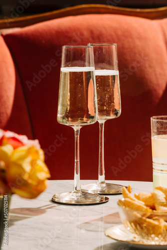 Prosecco flutes and snacks on a marbel table. Pink background