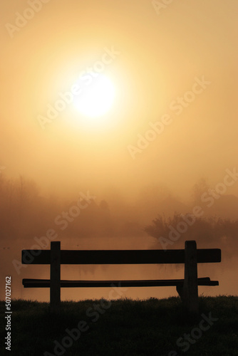 Vacant riverside bench on a foggy morning photo