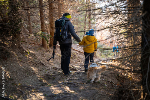 A mother with a child and a dog are walking along the mountain hiking trail. Family spending time. © Piotr