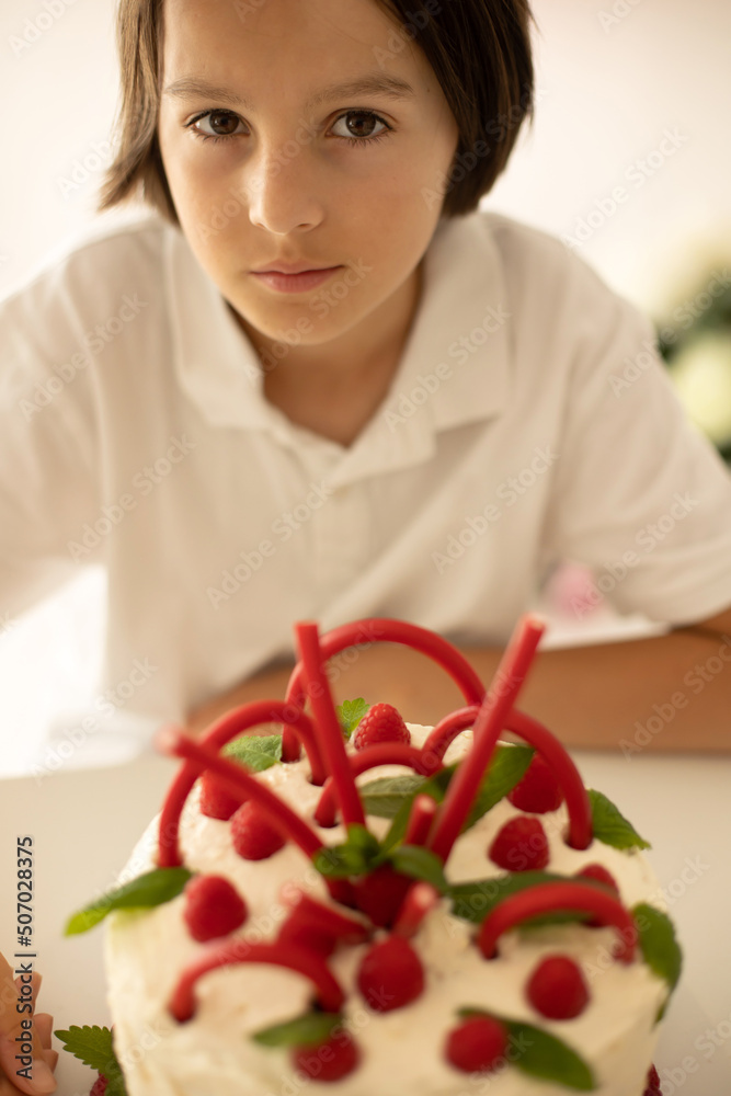 Cute child, preschool boy, celebrating birthday at home with homemade cake with raspberries, mint and candies Cute child, preschool boy, celebrating birthday at home with homemade cake with raspberries, mint and candies