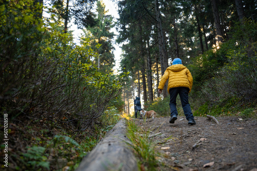 A mother with a child and a dog are walking along the mountain hiking trail. Family spending time. © Piotr