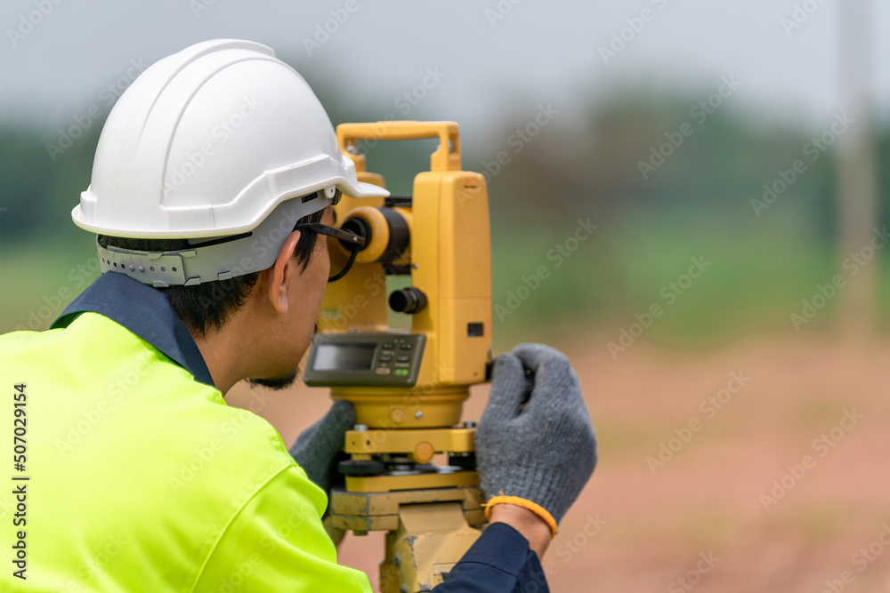 Surveyor Civil Engineer working theodolite or total positioning station on the construction site of the road or building with construction machinery background Surveyor Civil Engineer working theodolite or total positioning station on the construction site of the road or building with construction machinery background