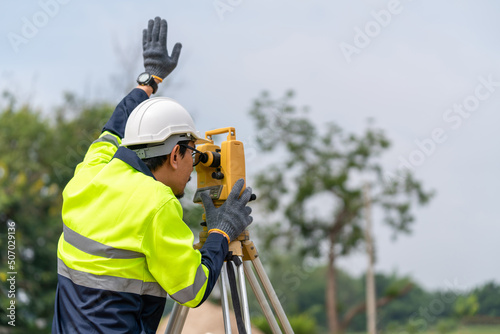 Asian Surveyor Civil Engineer working theodolite or total positioning station on the construction site.
