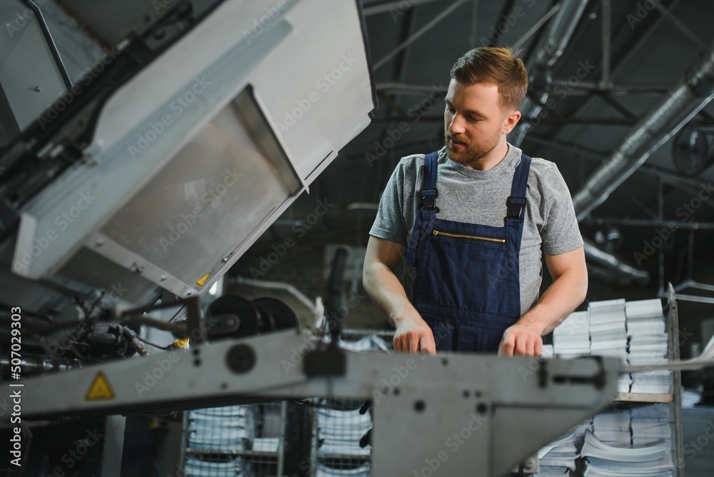 worker in protective clothing in factory using machine