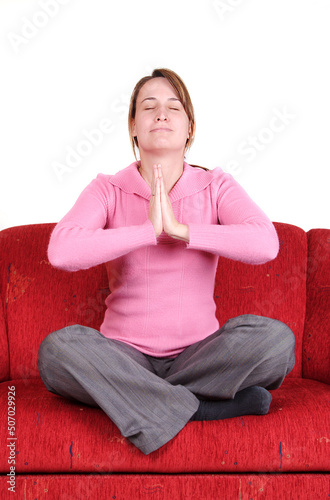 Young woman in yoga position on red couch at home photo