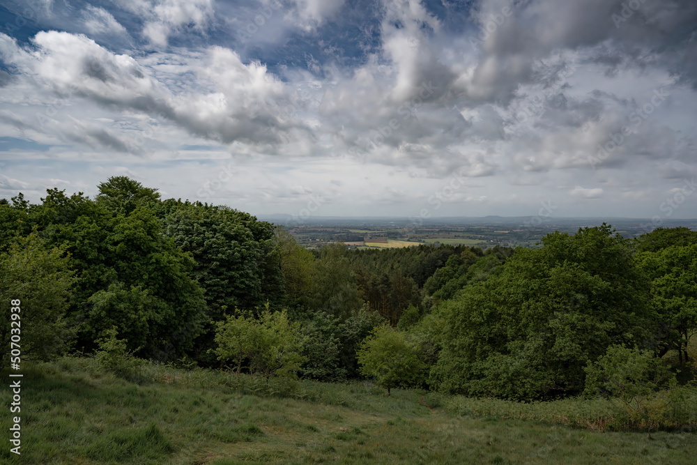 British hillside view over Worcestershire with trees and meadows under a cloudy sky
